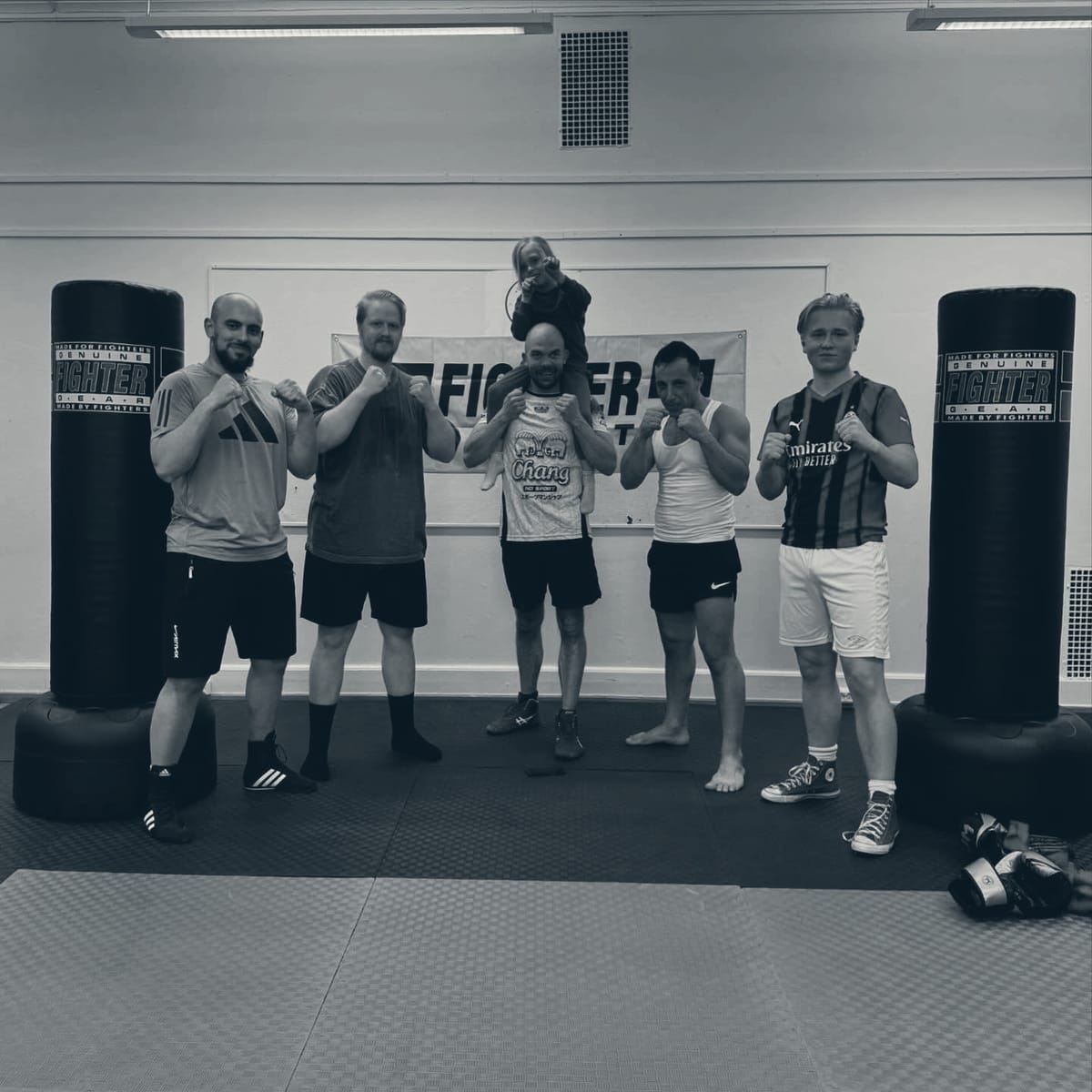 Sju boksere på rad foran Fighter Sport-banneret i klubblokalet