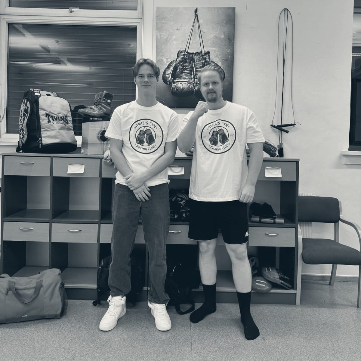 To medlemmer i hvite Omie's Gym-t-skjorter med klubbmerket på brystet